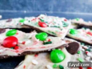 Close up shot of Christmas chocolate bark pieces, randomly stacked, with focus on one piece showcasing the layers and toppings.