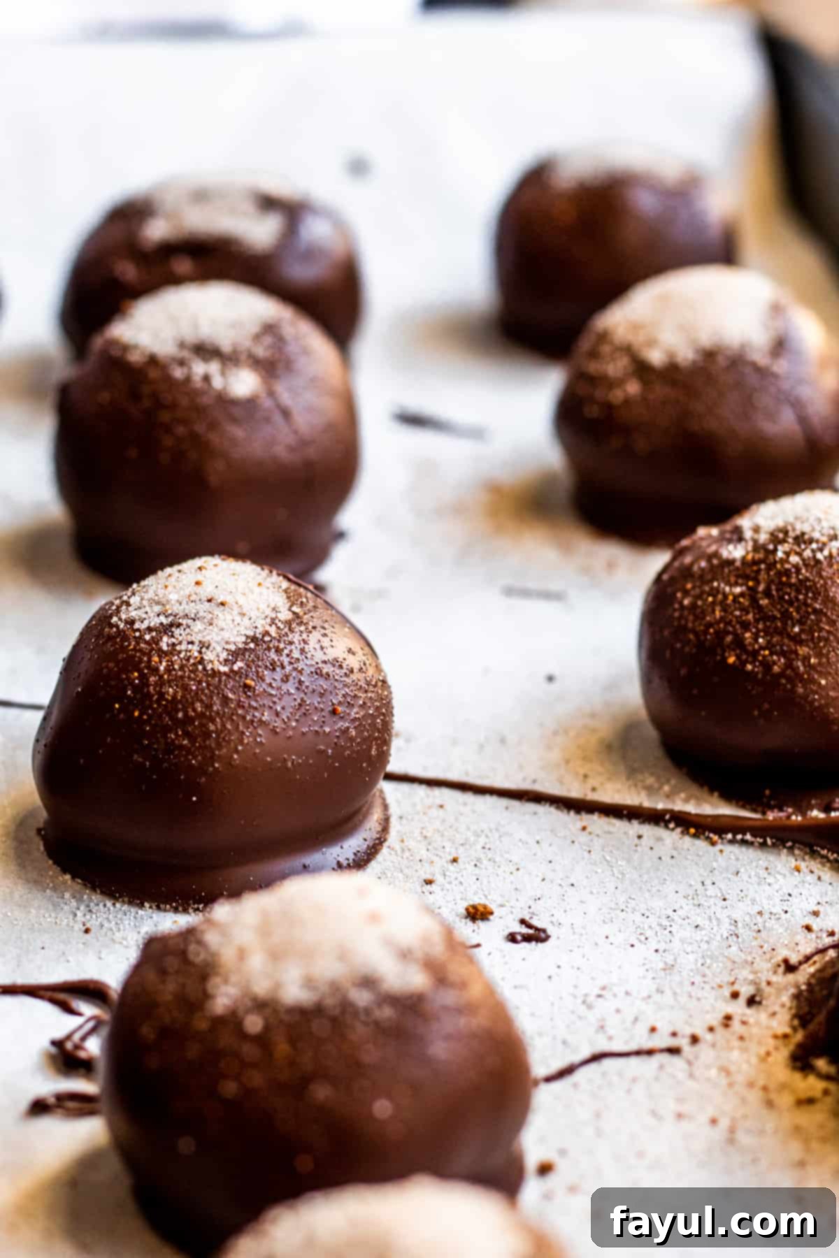 Truffles on parchment paper in rows, perfectly coated and spiced, ready for holiday enjoyment.