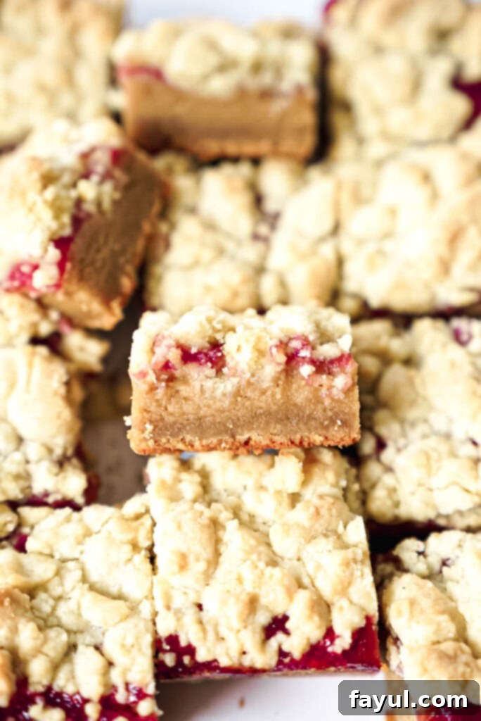 Ingredients for Peanut Butter and Jelly Bars laid out on a kitchen counter, including butter, sugars, eggs, peanut butter, flour, and a jar of strawberry jam.