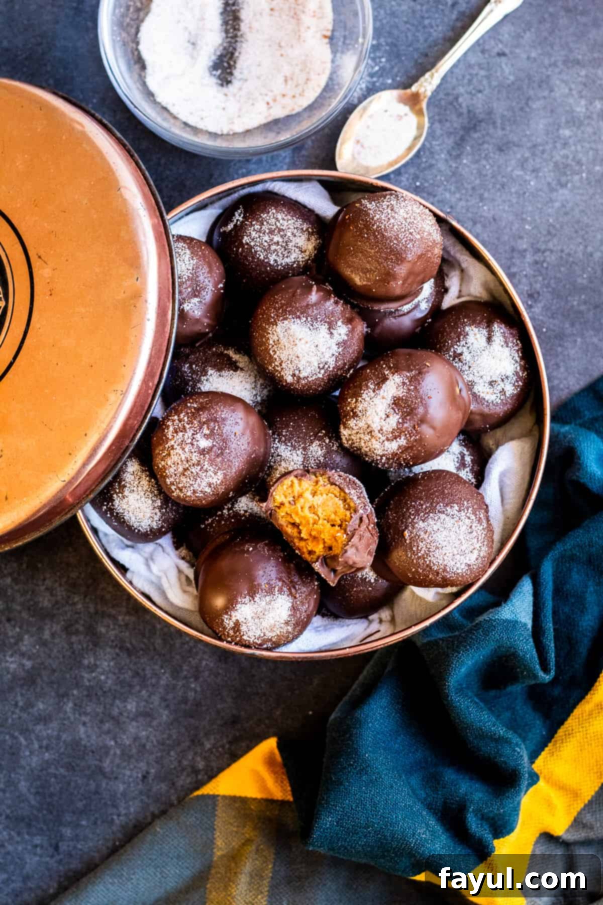 Overhead shot of gingerbread truffles in a decorative tin on a blue counter, ready for gifting.