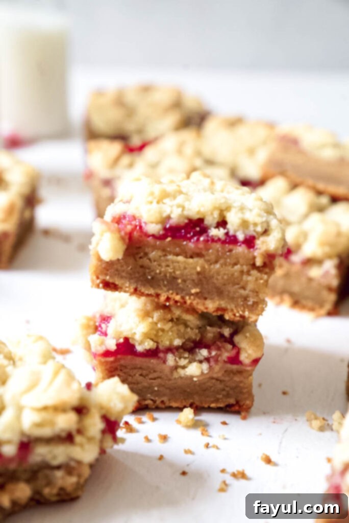 A stack of perfectly cut Peanut Butter and Jelly Bars on a white plate, ready to be enjoyed.