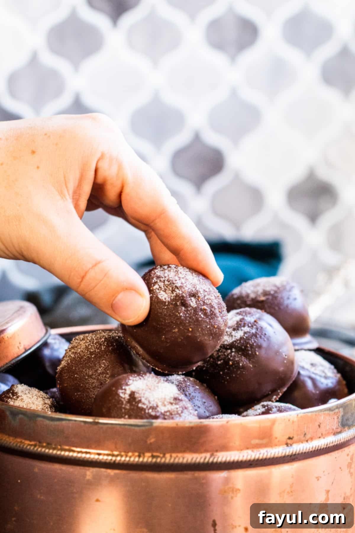 Hand picking up a gingerbread truffle from a tin, showcasing its appeal as a festive snack.