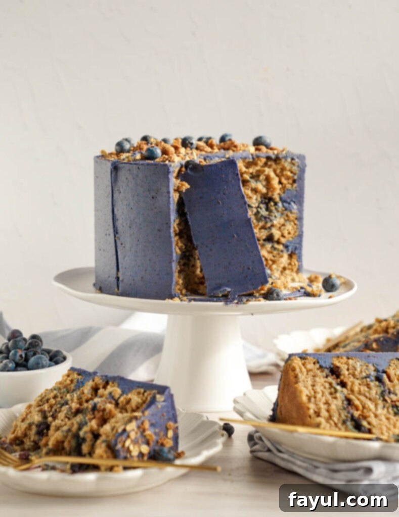 A beautifully decorated three-layer Blueberry Crisp Cake with fresh blueberries on top, ready to be served.