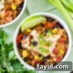 Overhead shot of a Crock Pot enchilada bake served in a white bowl, beautifully presented with a lime wedge and fresh herbs on the side.