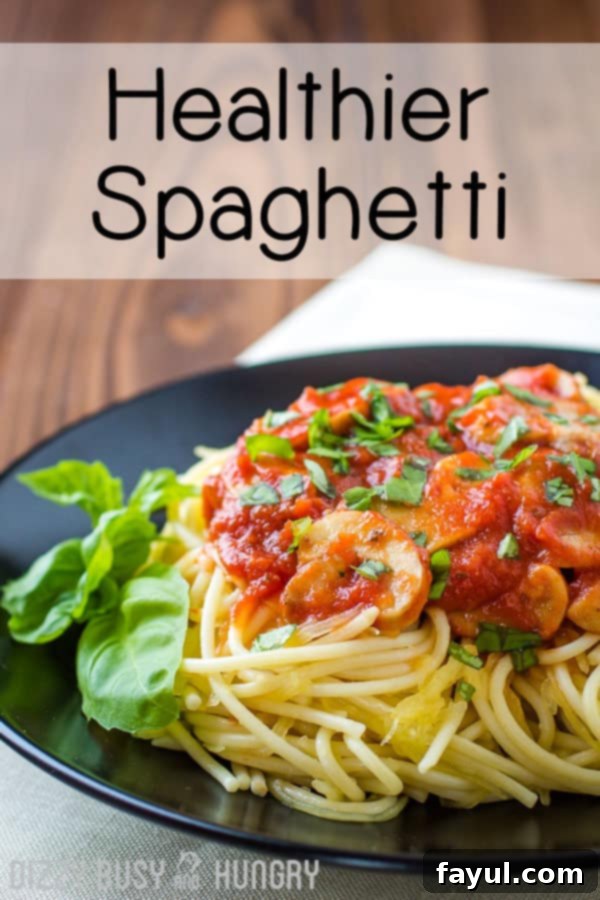Side view of a delicious spaghetti dinner, garnished with fresh herbs, served on a black plate against a rustic wooden background.