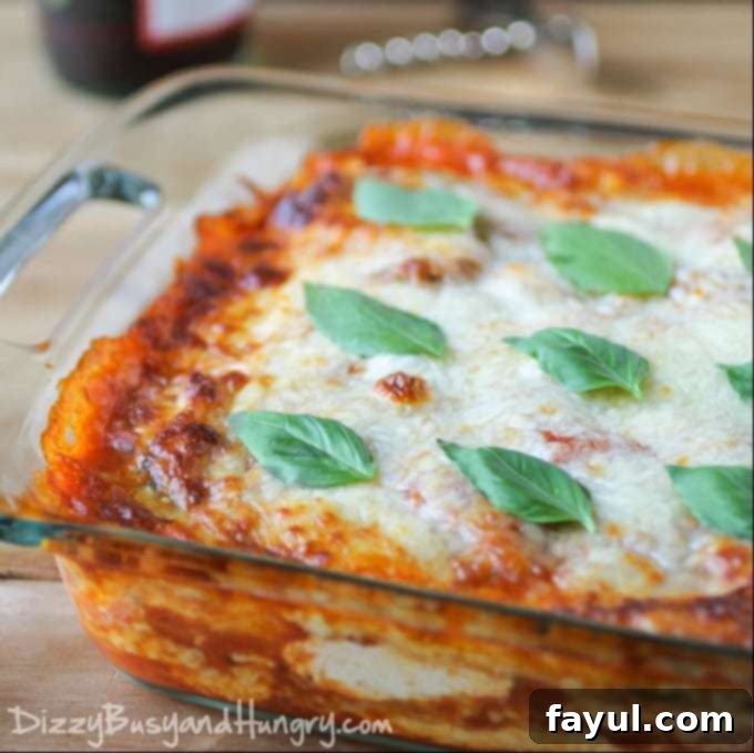 Side view of a vibrant eggplant polenta lasagna in a clear baking pan, beautifully topped with fresh basil.