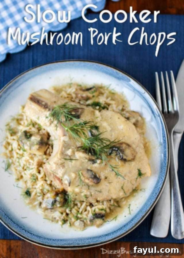 Overhead view of tender slow cooker mushroom pork chops, beautifully arranged on a blue and white plate with a fork and knife on the side.