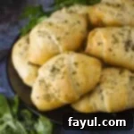 Side angled shot of savory zucchini cheese bites, neatly stacked on a black plate with fresh herbs adorning the side.