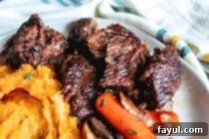 Image for crockpot beef short ribs recipe. Close up shot of the beef on a white plate with a white napkin in the background. 
