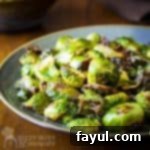 Side shot of garlic roasted Brussel sprouts on a blue and grey plate on a wooden table.
