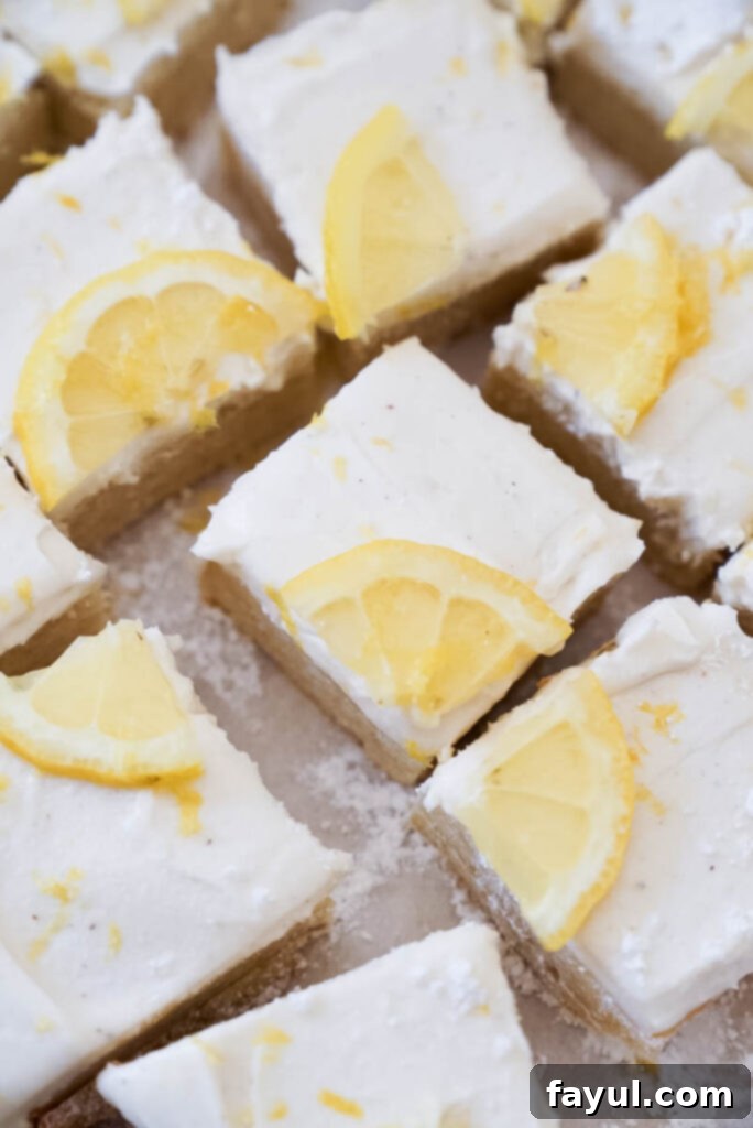 Close-up of a square lemon cookie bar with cream cheese frosting and lemon zest on top