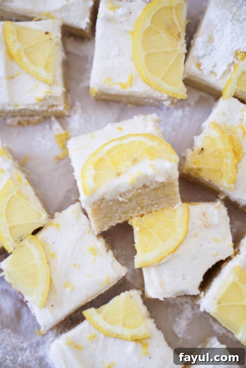 Cream cheese frosting being spread smoothly over cooled lemon cookie bars