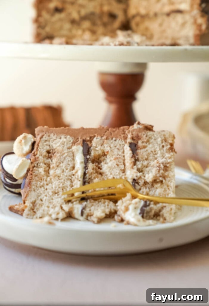 Close-up of a slice of Churro S'mores Cake showcasing the cinnamon cake layers, chocolate ganache, and marshmallow filling.