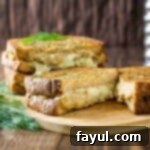 Side view of grilled cheese cut in half with dill on the side.