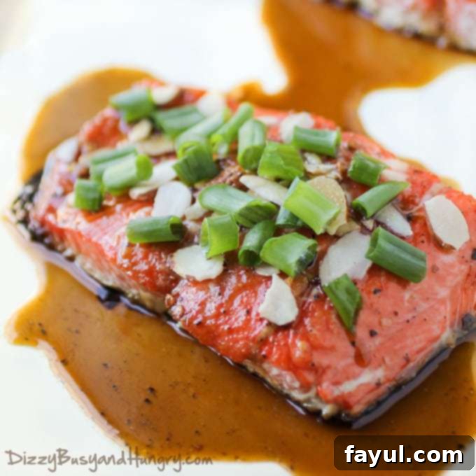Close up view of cooked salmon sprinkled with sliced almonds and scallions.