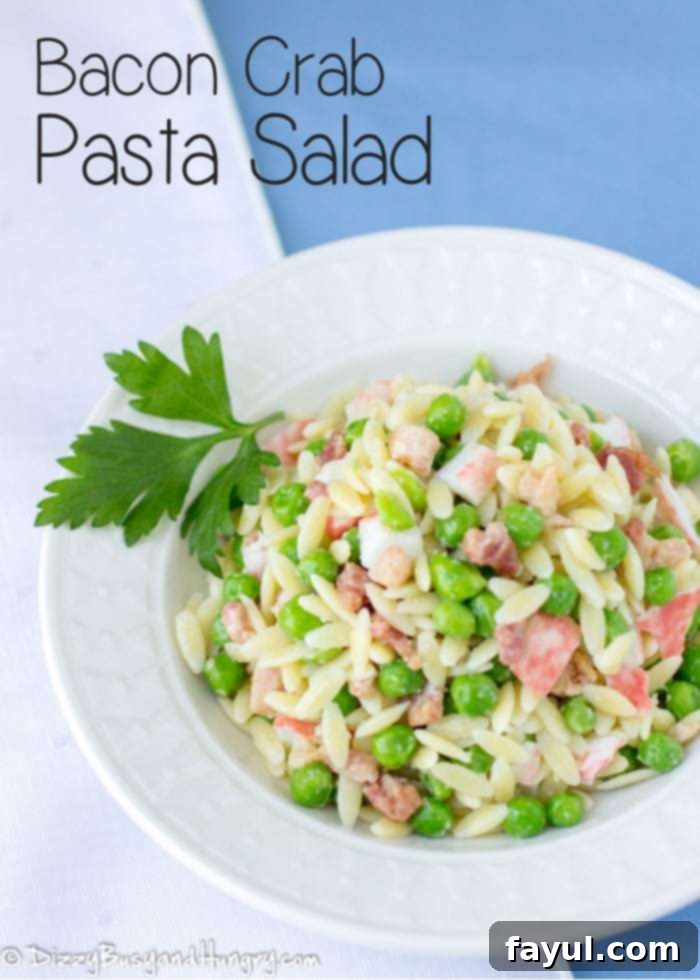 Overhead view of bacon crab pasta salad in a white bowl on a blue background garnished with parsley.