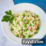 Overhead shot of crab pasta salad in a white bowl garnished with fresh parsley.