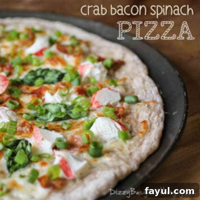 Side view of half bacon crab spinach pizza on a dark pizza tray garnished with scallions.