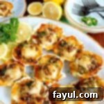 Top view of 9 baked sea scallops on a white serving tray surrounded by garnish