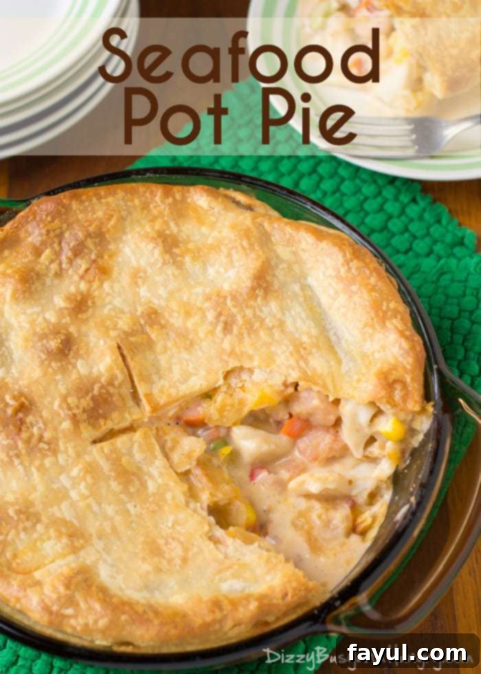 Overhead view of cooked pot pie with flaky crust with a slice missing so you can see the creamy, seafood-packed inside.