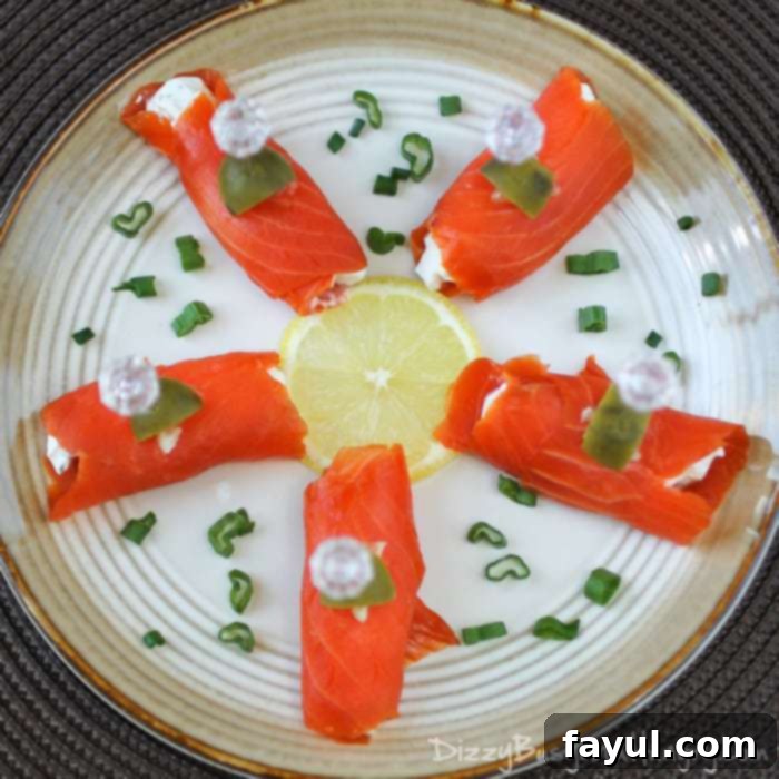 Overhead view of 5 salmon bites arranged on a white plate like the spokes of a wheel with a round lemon slice in the center.