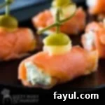Side view of multiple smoked salmon bites on a black plate.
