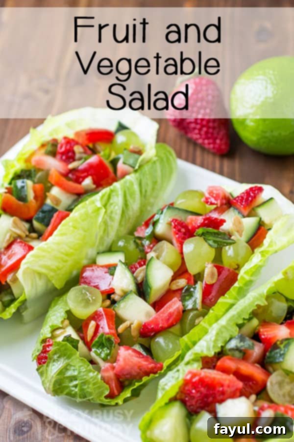 A colorful fruit and vegetable salad spooned into crisp romaine lettuce leaves and elegantly arranged on a white platter, inviting summer freshness.