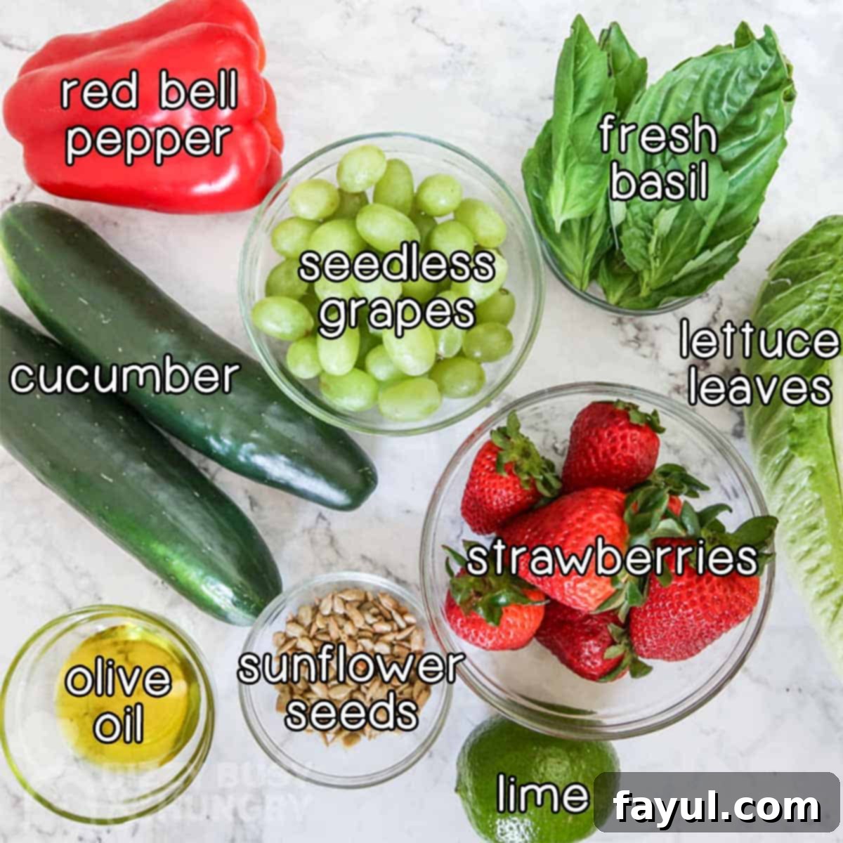An overhead view showcasing all the fresh, colorful ingredients laid out on a white surface, ready to be chopped for this vibrant vegan fruit and vegetable salad.