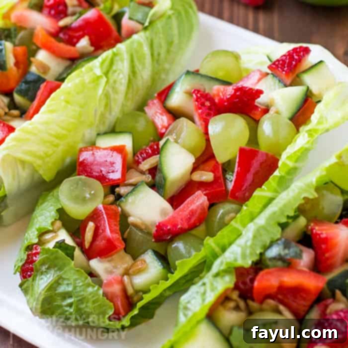 A close overhead view of this vibrant summer salad elegantly served as a romaine lettuce boat, garnished with a sprinkle of sunflower seeds and fresh basil, ready for enjoyment.
