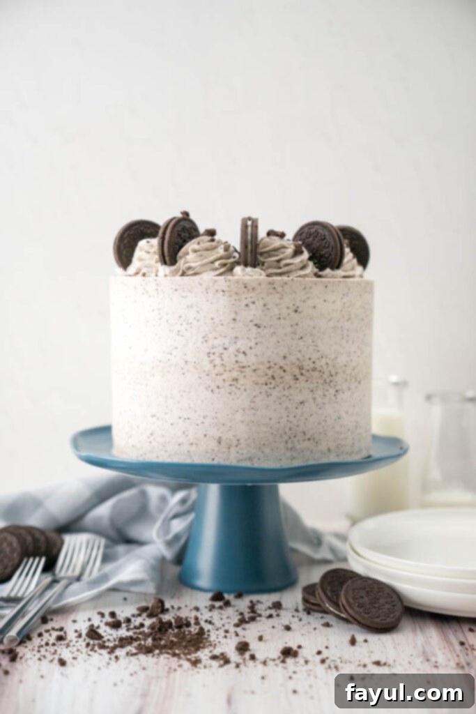 A stunning slice of the Ultimate Cookies and Cream Cake, showcasing its distinct layers of dark chocolate cake, white cream cheese filling, and Oreo buttercream, sitting on an Oreo cookie crust.