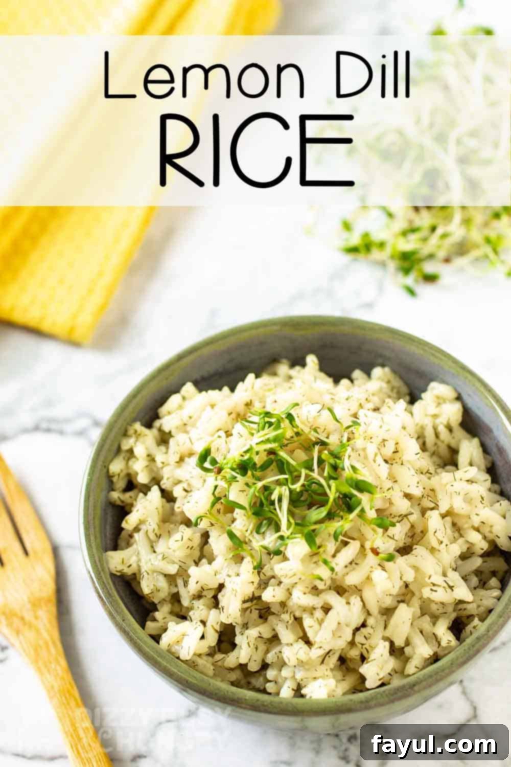 Close up overhead shot of lemon dill rice garnished with herbs in an olive green bowl on a marble table with a yellow cloth and wooden spoon on the side.