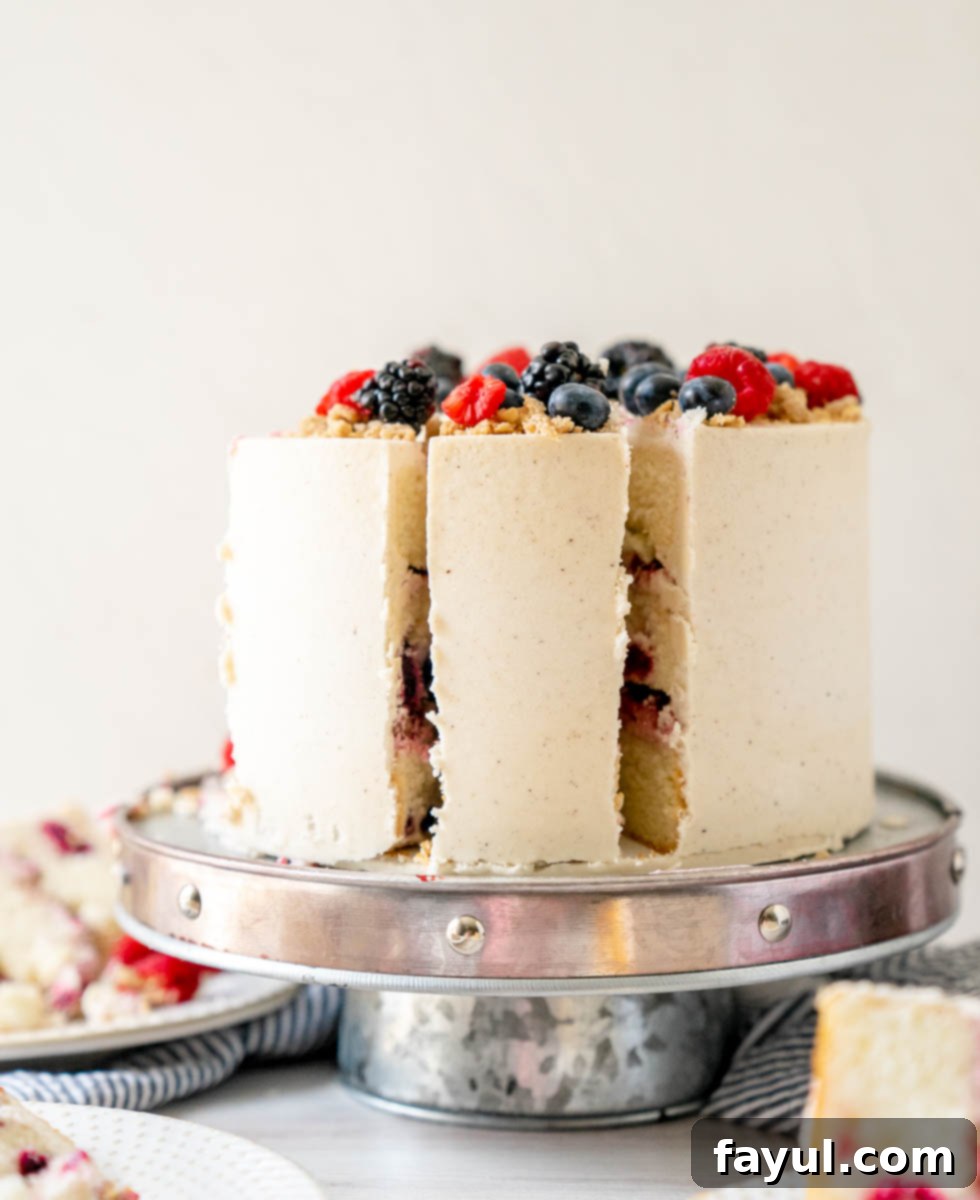 Overhead shot of a whole Triple Berry Cake, garnished with fresh berries and oat crumble.
