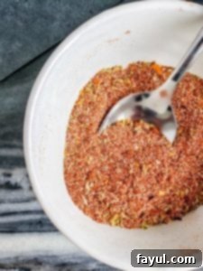 Homemade taco seasoning in a white bowl with a silver spoon, ready to be used.