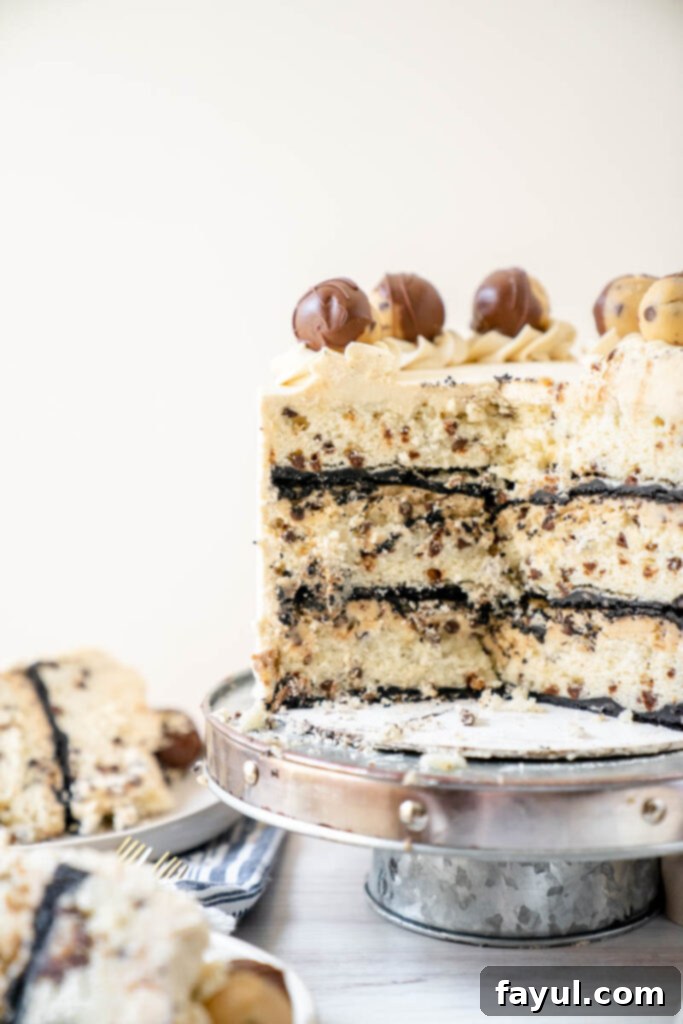 A slice of Cookie Dough Cake showing the layers of cake, cookie dough, and frosting.