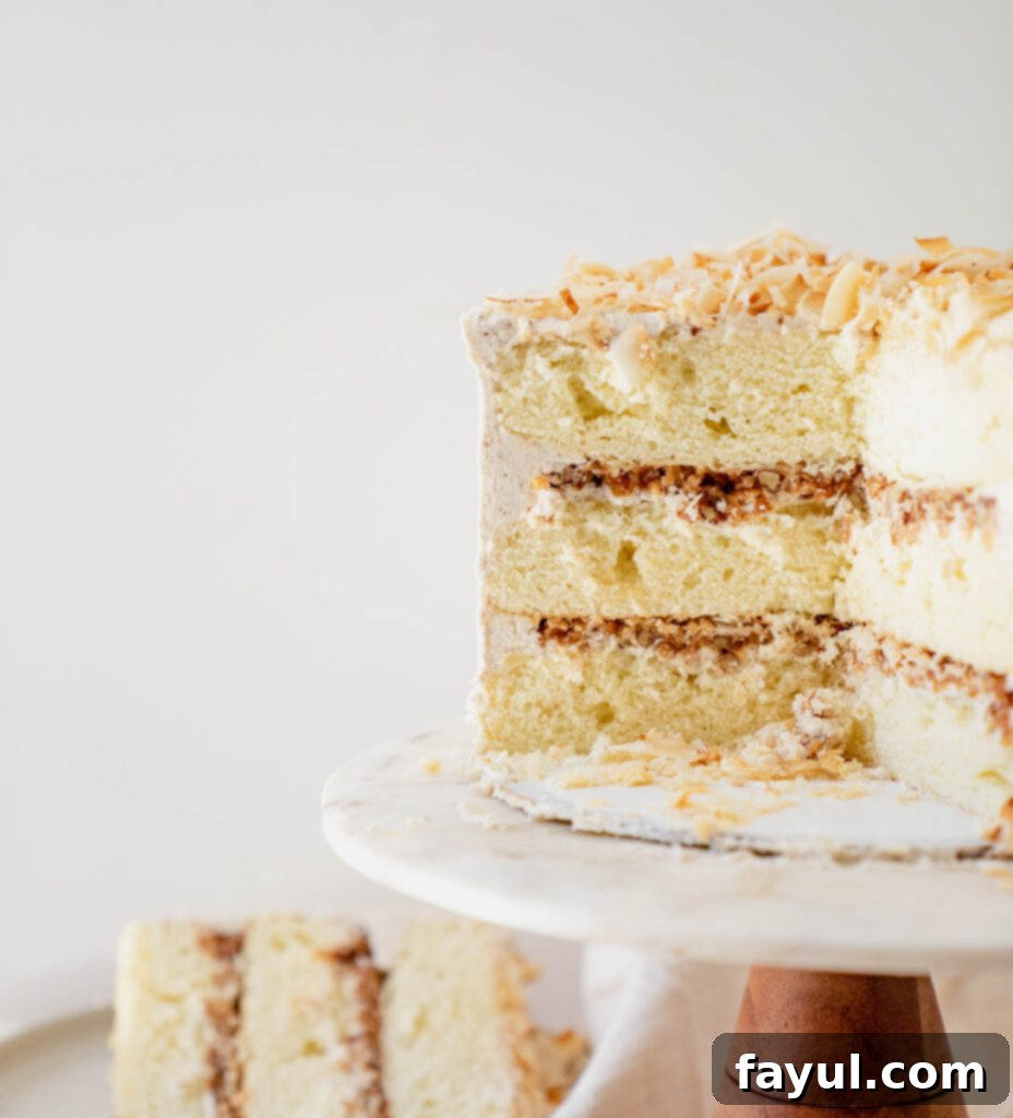A slice of Coconut Caramel Pecan Cake on a plate, showing the moist cake, rich filling, and fluffy buttercream.