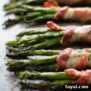 Close up image of perfectly cooked bacon wrapped asparagus on a baking sheet, ready to serve.
