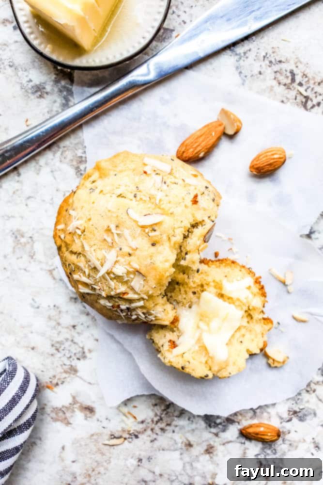 Overhead shot of broken muffin with butter on it on a white counter.