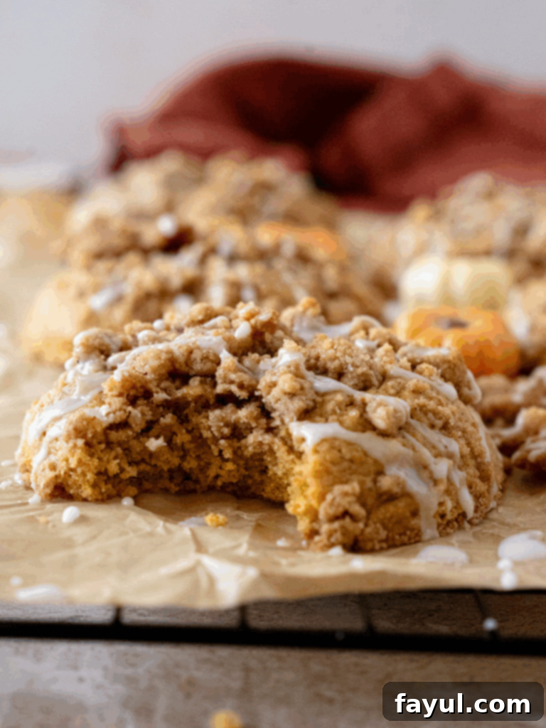 Delicious Pumpkin Coffee Cake Cookies with a generous streusel topping, glistening with icing drizzle on a white background.