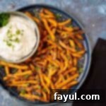 Top-down view of vibrant air-fried sweet potato fries piled on a blue plate with a side of ranch mayo.