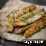 Close-up side shot of multiple baked dill French fries garnished with green herbs.