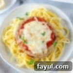 Beautifully air fried eggplant parmesan round over a bed of spaghetti topped with chopped parsley.