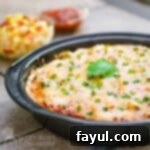 Close up view of fiesta lasagna garnished with green onions in a black pan.