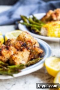 Grilled chicken on blue plate with veggies and lemons. 