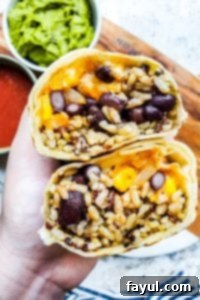 Hand holding two halves of burrito close to the camera. 