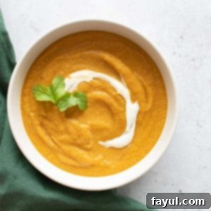 A bowl of carrot and lentil soup, topped with Greek yogurt and cilantro, showcasing its creamy texture and fresh garnish.