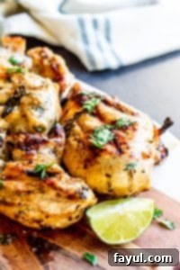 Sliced Cilantro Lime Grilled Chicken arranged on a rustic wooden cutting board with fresh lime and cilantro garnish.