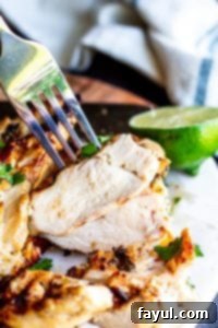 Close-up of a juicy piece of grilled cilantro lime chicken being lifted with a fork, showcasing its tender texture.