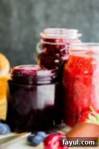 Strait on shot of three jams in glass containers with gray background.