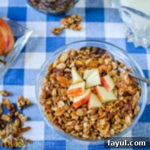 Top down view of homemade granola in a glass bowl with a spoon in it.