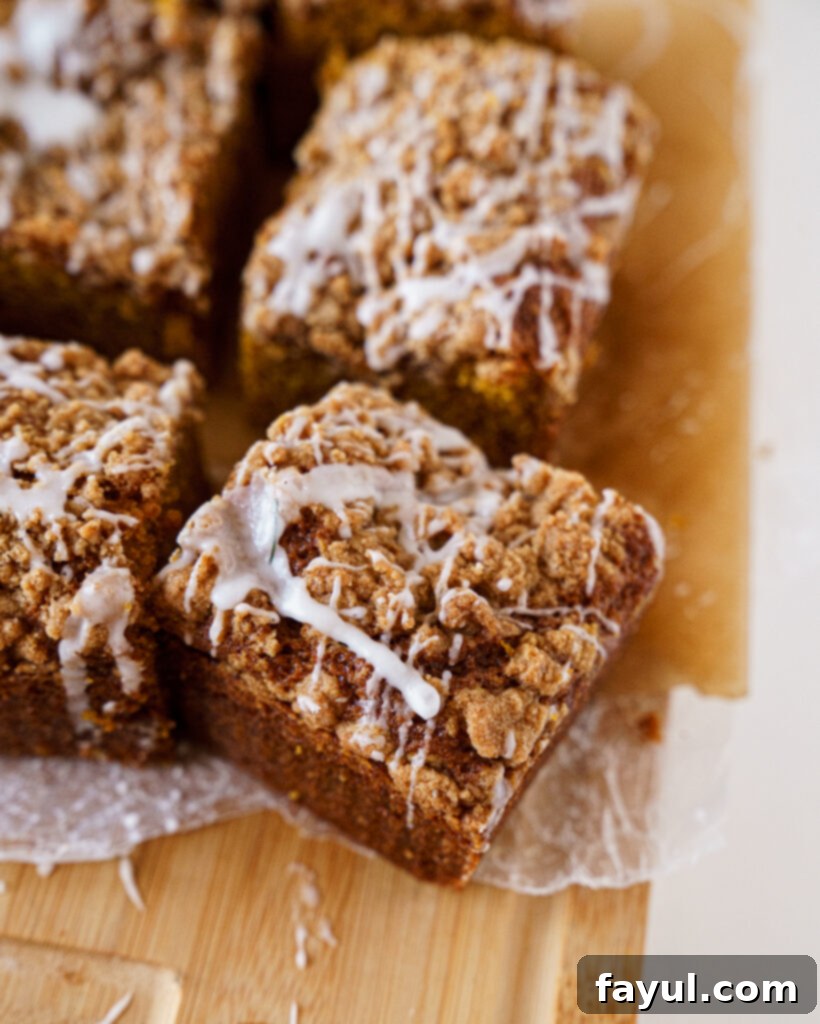 A whole glazed pumpkin coffee cake in a square pan with a slice removed.
